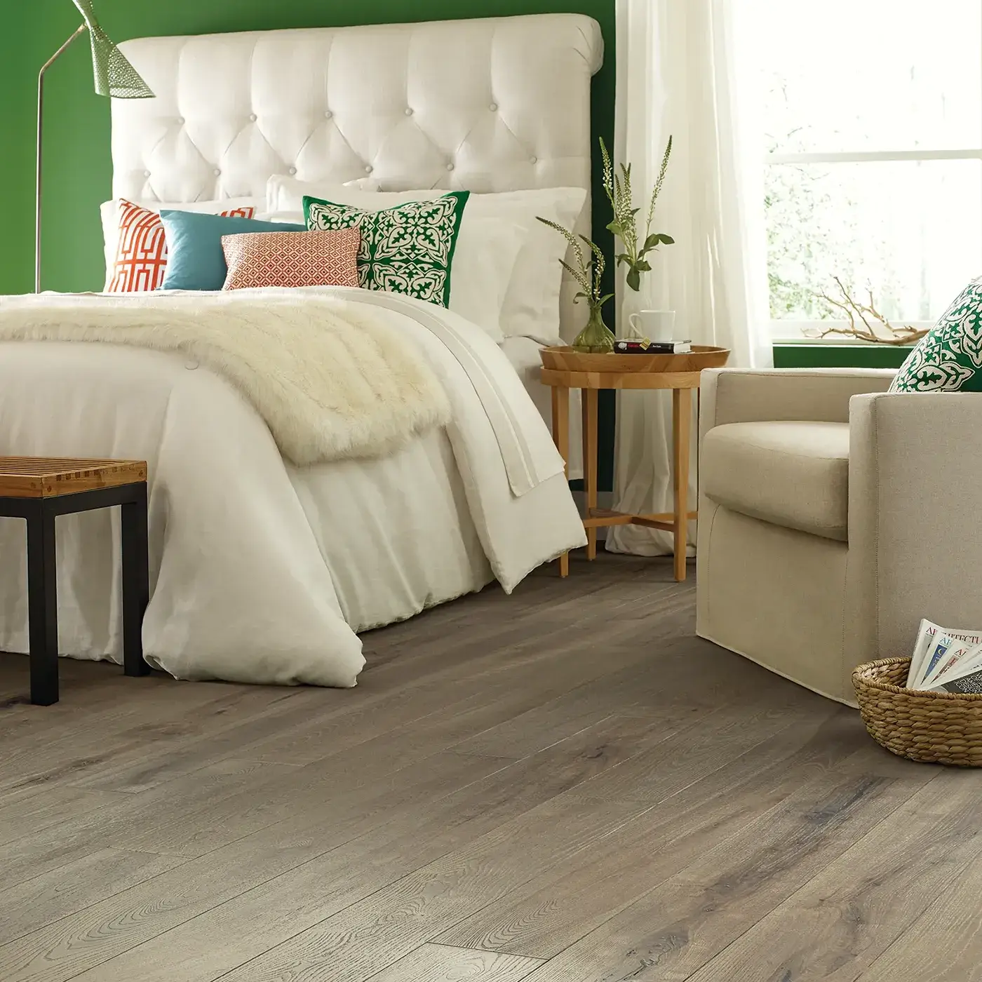 Gray-toned hardwood in a bedroom with a white tufted headboard | Kirkland's Flooring
